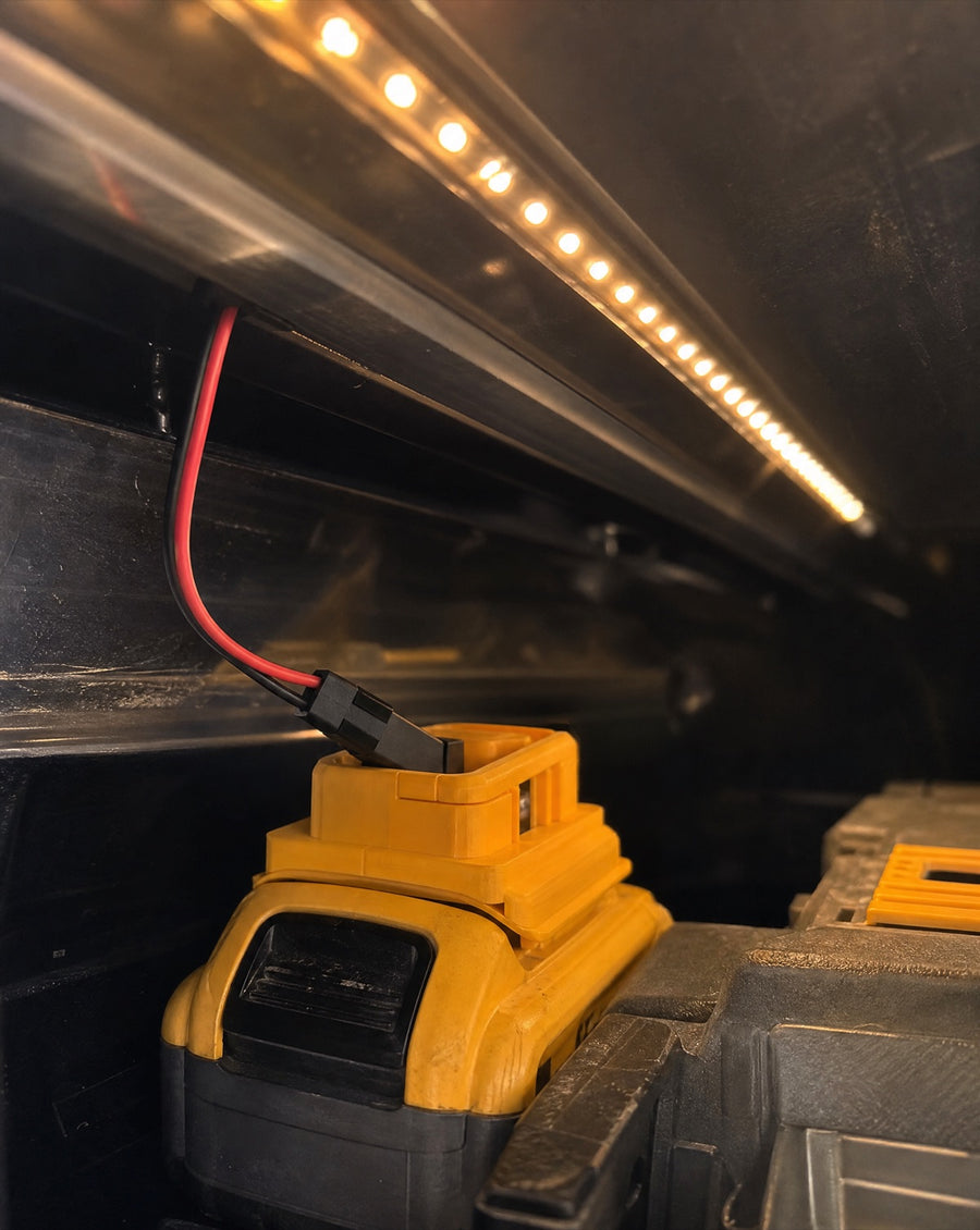 Battery adapter clipped to a 20V/18V tool battery inside a truck cap setup