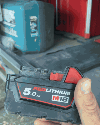 Clipping an M18 battery onto the LumoLux adapter under a truck cap