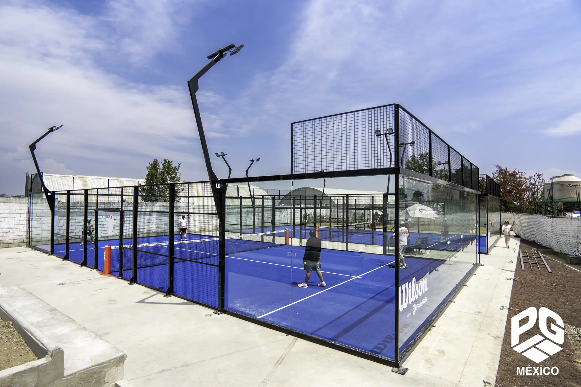 Two players engaged in a game on a blue padel court surrounded by glass walls.