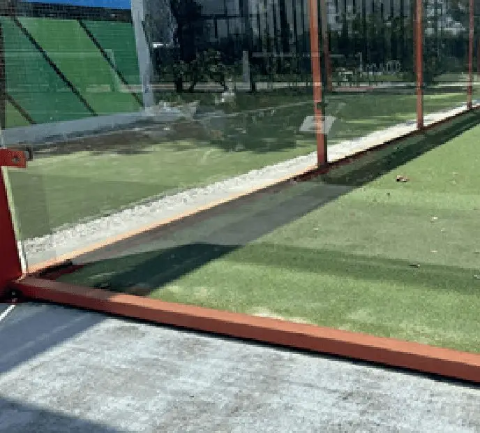 Red metal fence enclosing a grass surface area in an outdoor setting.