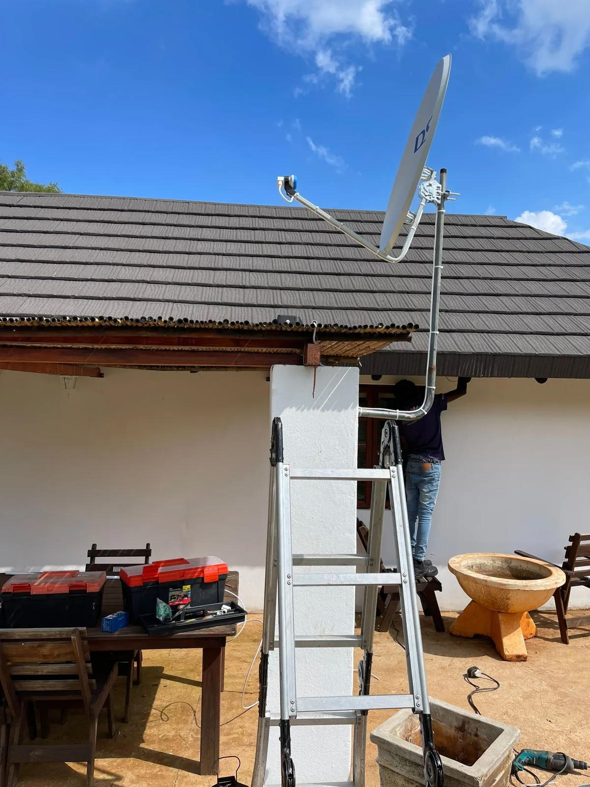 DStv technician on a ladder performing a tiled roof satellite dish installation