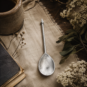 Handcrafted pewter well spoon on rustic linen