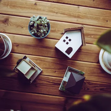 Miniature houses, a succulent, and plant pots on a wooden table.