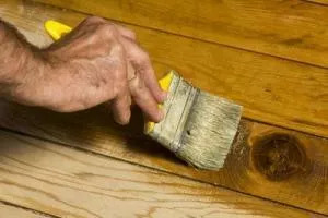 person uses brush to stain hardwood floor