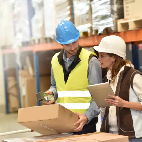 Store manager with warehouseman checking stock levels in industrial facility